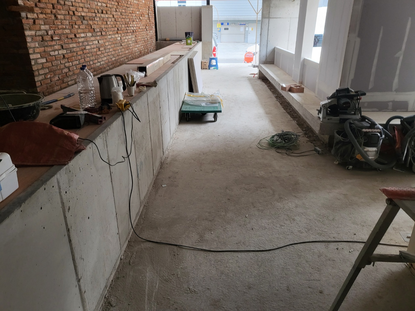 현장에서 공사 작업이 진행 중인 모습입니다. (지역에서, 면적) · 자연광이 어우러져 콘크리트의 고급스러운 질감이 드러납니다.